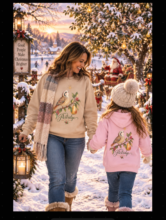 Mom and daughter wearing matching Partridge in a Pear Tree Christmas sweatshirt and pink kids hoodie in a magical snowy outdoor scene